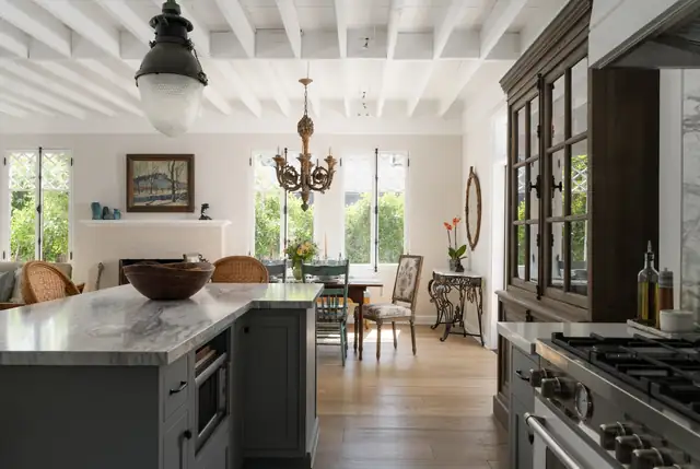 Santa Barbara kitchen by Kellow Construction with a charcoal island, a marble top, an iron pendant and a glass-front hutch