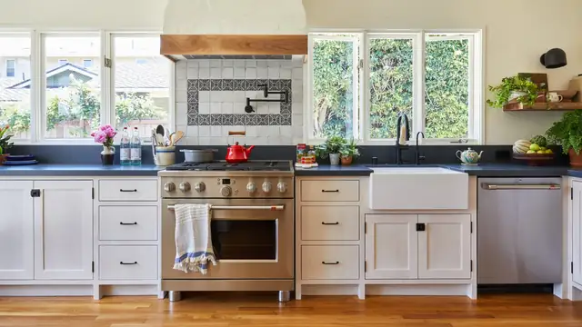 Remodeled Santa Barbara kitchen with white cabinets, a farmhouse sink, a professional range and a patterned tile backsplash under a plaster hood